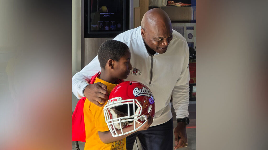 Former Buffalo Bills cornerback JD Williams presents a signed Fresno State football helmet to a Thomas Elementary School Student