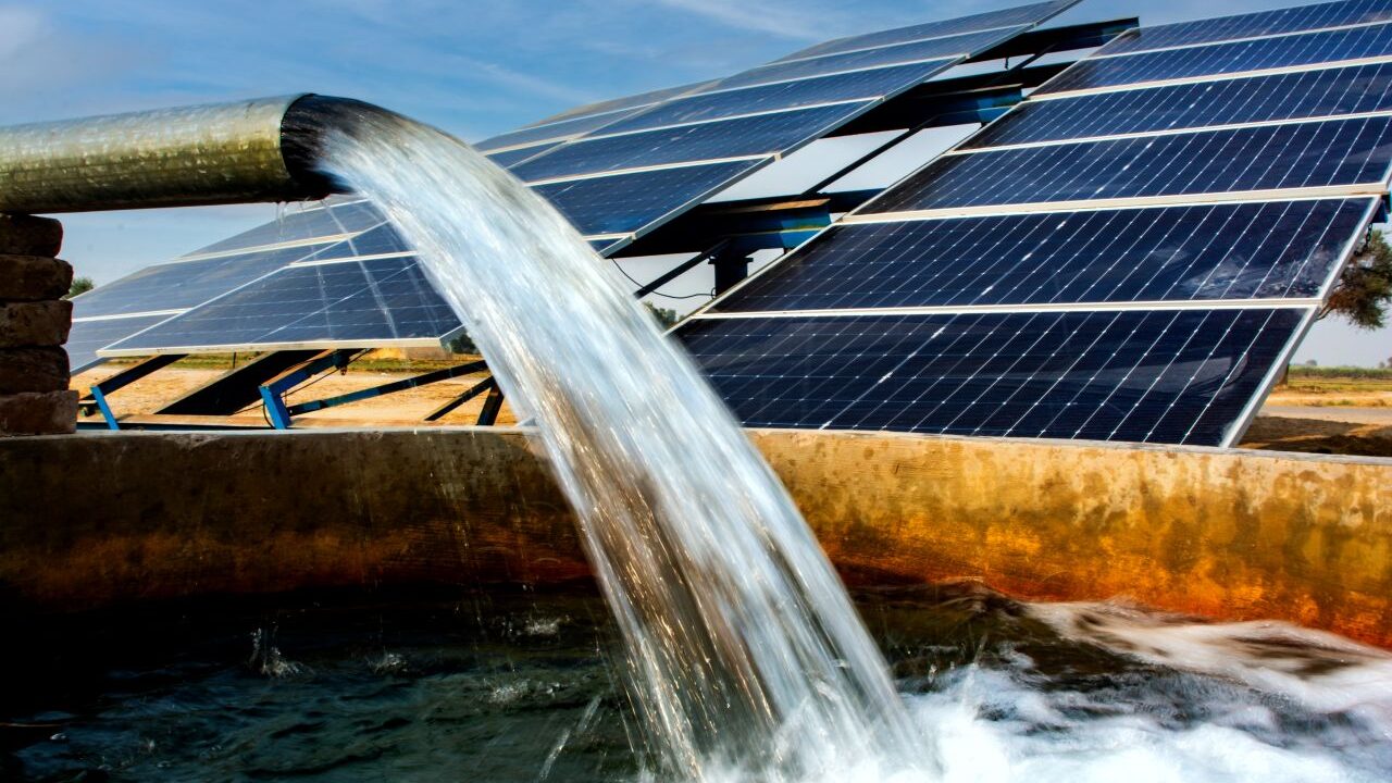 Image of a solar powered well pouring out water for irrigation.