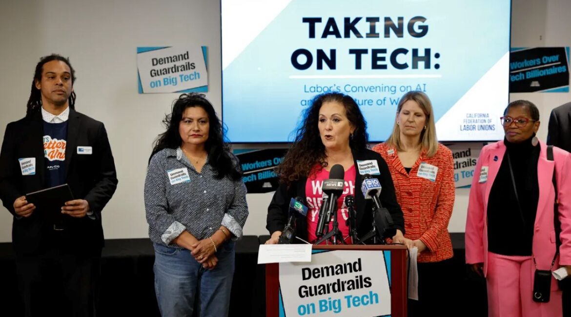 Image of labor leader Lorena Gonzales, in blue jacket and red t-shirt, flanked by other union leaders