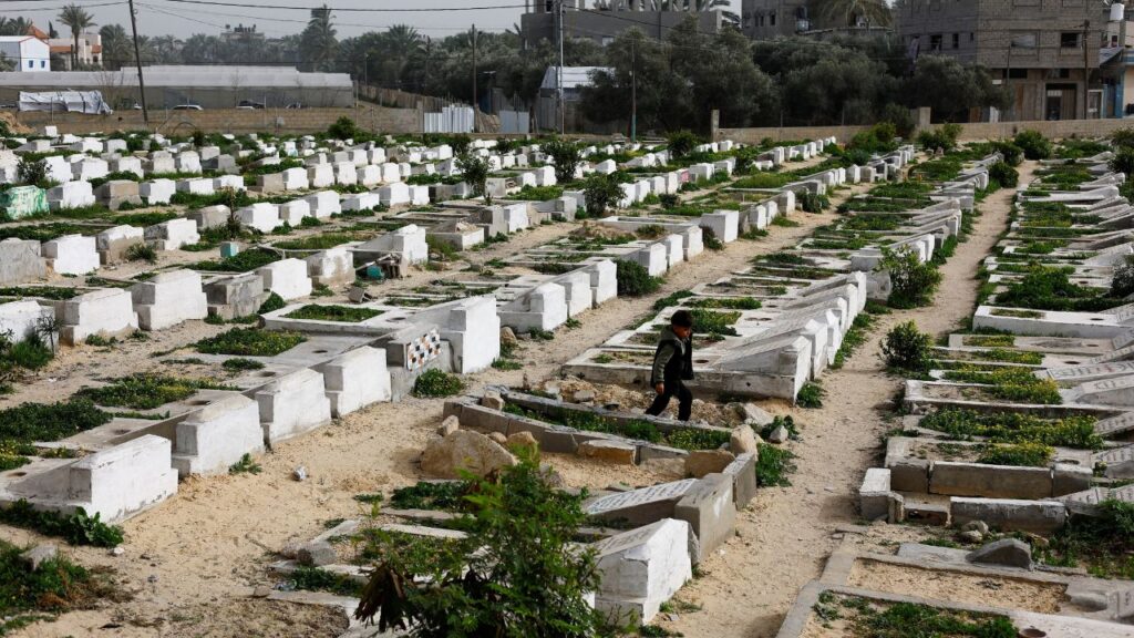 A Palestinian child walks through the cemetery with graves of some of those killed during the war, in Deir al-Balah, central Gaza Strip, January 30, 2026. (Reuters/Mahmoud Issa)