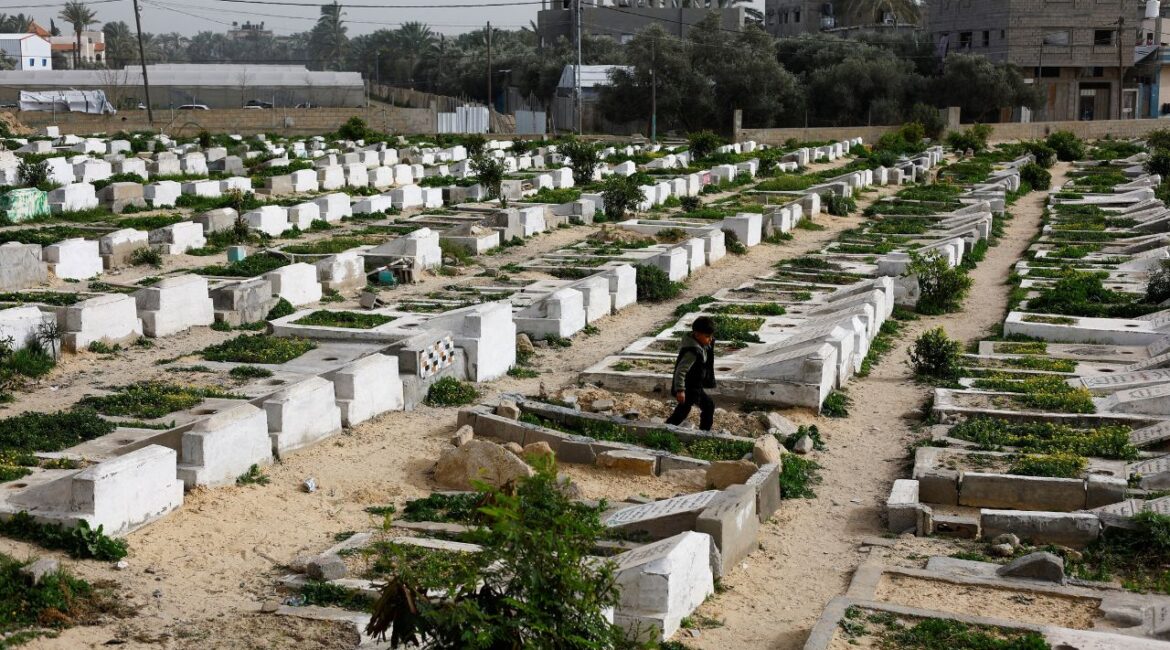 A Palestinian child walks through the cemetery with graves of some of those killed during the war, in Deir al-Balah, central Gaza Strip, January 30, 2026. (Reuters/Mahmoud Issa)