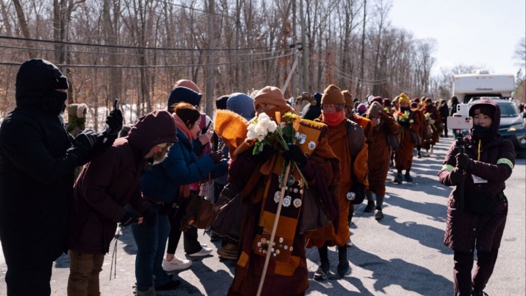 A group of Buddhist monks who walked all the way from Texas receive offerings from supporters as they arrive in Triangle, Va., about 40 miles from Washington, their final destination, on Satutday, Feb. 7, 2026. A diverse swath of Americans searching for calm say they found some as the group of Buddhist monks finished their 2,300-mile trek. (Caroline Gutman/The New York Times)