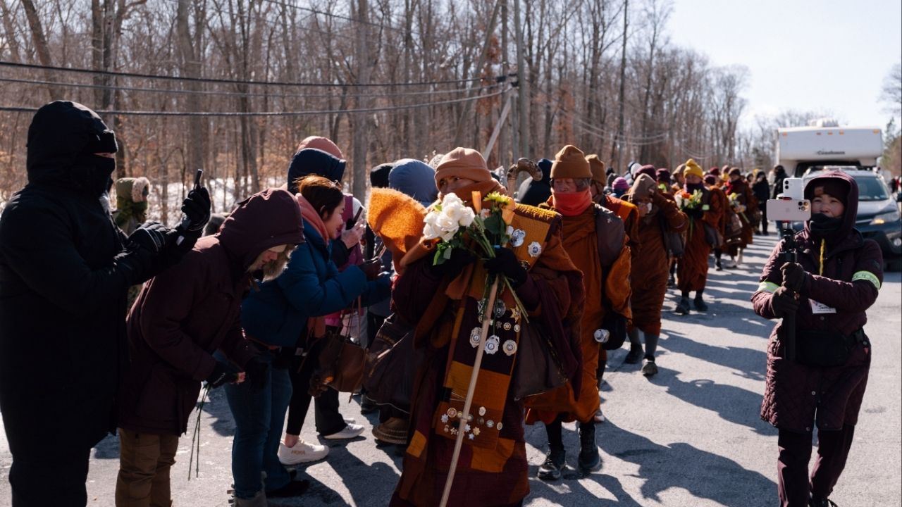 A group of Buddhist monks who walked all the way from Texas receive offerings from supporters as they arrive in Triangle, Va., about 40 miles from Washington, their final destination, on Satutday, Feb. 7, 2026. A diverse swath of Americans searching for calm say they found some as the group of Buddhist monks finished their 2,300-mile trek. (Caroline Gutman/The New York Times)