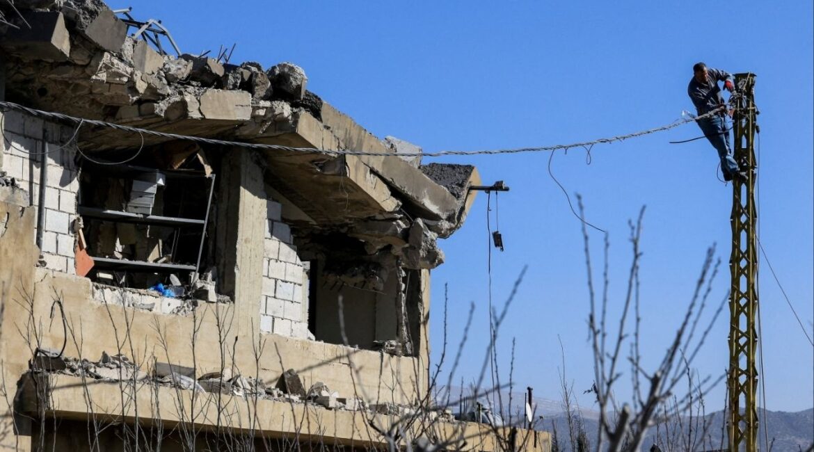 A man works on an electric pole next to a damaged building, in the aftermath of an Israeli strike on Friday, in Tamnine el Tahta, Bekaa valley, Lebanon, February 21, 2026. (Reuters/Mohamed Azakir)