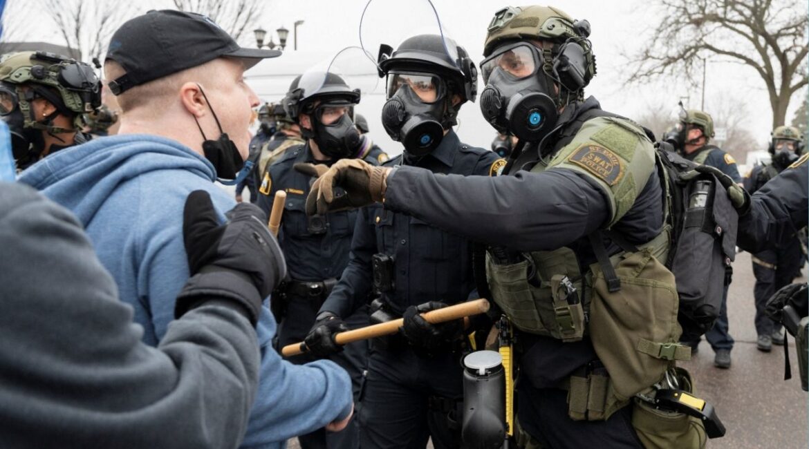A protester faces law enforcement officers after federal immigration agents raided a home in St. Paul, Minnesota, U.S., November 25, 2025. (Reuters/Tim Evans)