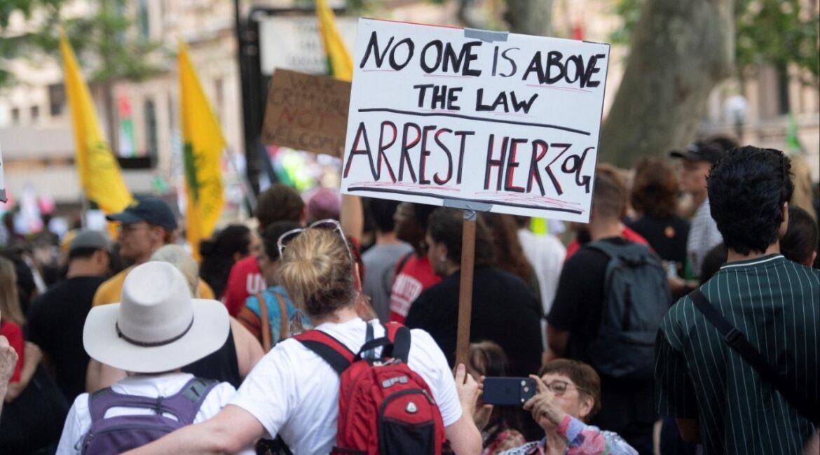A protester holds a sign as demonstrators gather at Town Hall Square to protest against Israeli President Isaac Herzog's state visit to Australia following a deadly mass shooting during a Jewish Hanukkah celebration at Bondi Beach on December 14, in Sydney, Australia, February 9, 2026. (Reuters/Jeremy Piper )