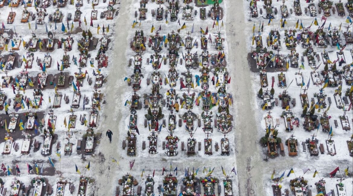 A visitor walks amid hundreds of graves of fallen Ukrainian soldiers in Lviv, Ukraine, Feb. 24, 2026. Some estimates indicate that Ukraine has lost more soldiers as a proportion of its wartime population than Russia has, even if Russian losses have been far larger overall. (Mauricio Lima/The New York Times)