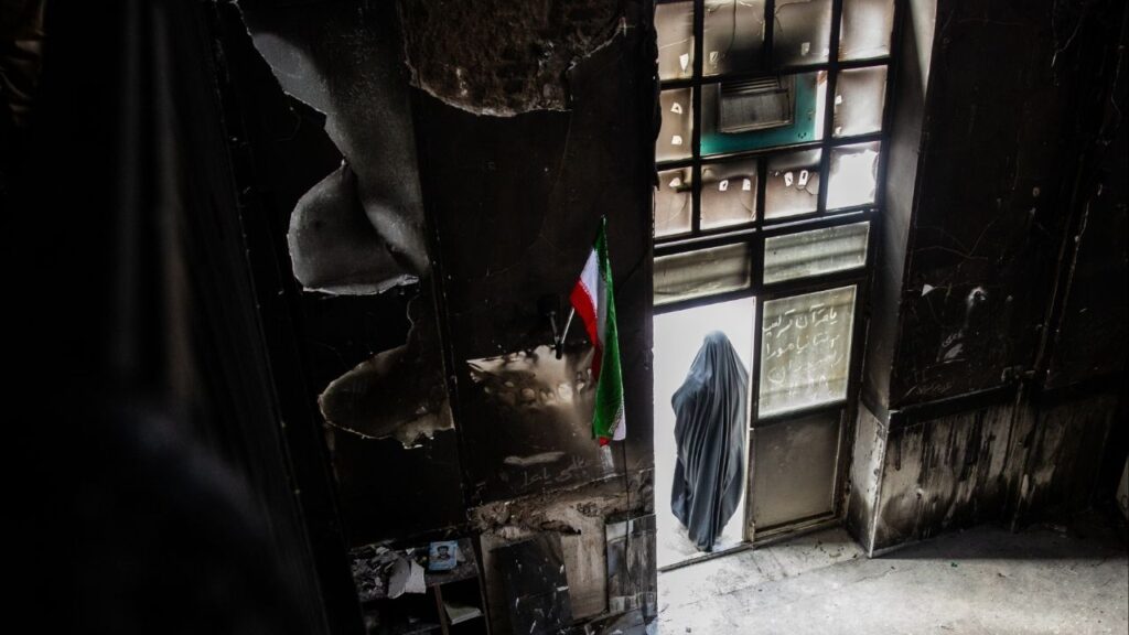 A woman at the door of a mosque that was burned during protests, in Tehran, Iran. Jan. 21, 2026. Families across Iran will commemorate the end of the traditional Iranian Islamic 40-day mourning period this week for loved ones killed at the peak of a bloody crackdown on nationwide protests demanding an end to authoritarian clerical rule. (Arash Khamooshi/The New York Times)