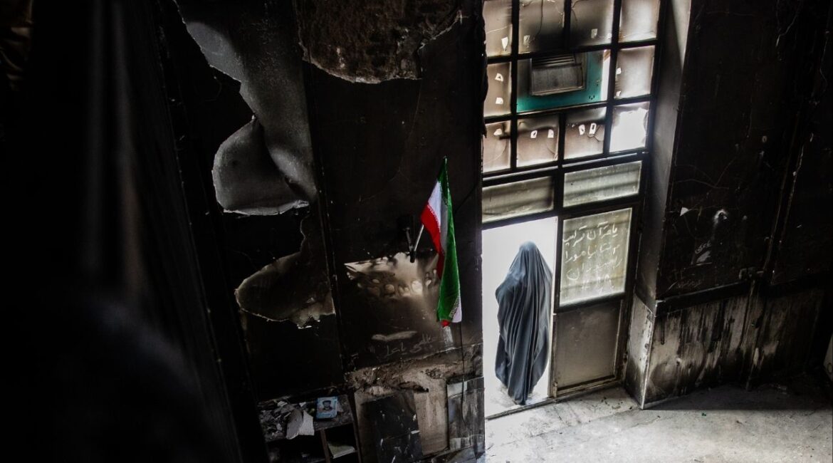 A woman at the door of a mosque that was burned during protests, in Tehran, Iran. Jan. 21, 2026. Families across Iran will commemorate the end of the traditional Iranian Islamic 40-day mourning period this week for loved ones killed at the peak of a bloody crackdown on nationwide protests demanding an end to authoritarian clerical rule. (Arash Khamooshi/The New York Times)