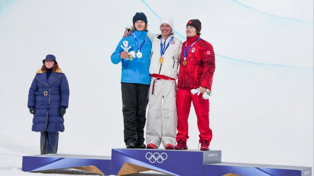 Alex Ferreira of the U.S. celebrates winning gold, joined by silver medalist Henry Sildaru of Estonia, left, and bronze medalist Brendan Mackay of Canada, right in the freestyle men’s freeski halfpipe final, during the 2026 Milan Cortina Winter Olympics in Livigno, Italy, on Friday, Feb. 20, 2026. (Gabriela Bhaskar/The New York Times)
