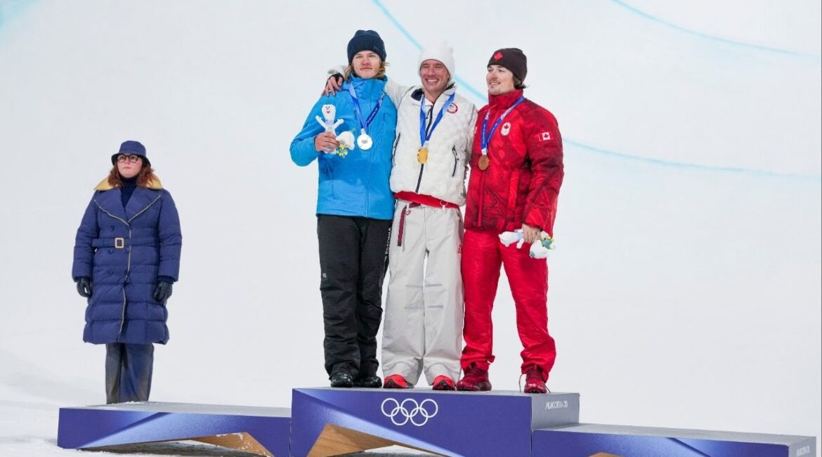 Alex Ferreira of the U.S. celebrates winning gold, joined by silver medalist Henry Sildaru of Estonia, left, and bronze medalist Brendan Mackay of Canada, right in the freestyle men’s freeski halfpipe final, during the 2026 Milan Cortina Winter Olympics in Livigno, Italy, on Friday, Feb. 20, 2026. (Gabriela Bhaskar/The New York Times)