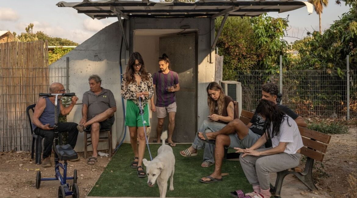 People sit near a bomb shelter between sirens during an Iranian missile attack in Rishpon, Israel, June 24, 2025. The national mood is somewhere between anxiety, resignation and anticipation as President Donald Trump considers whether to attack Iran. (Avishag Shaar-Yashuv/The New York Times)