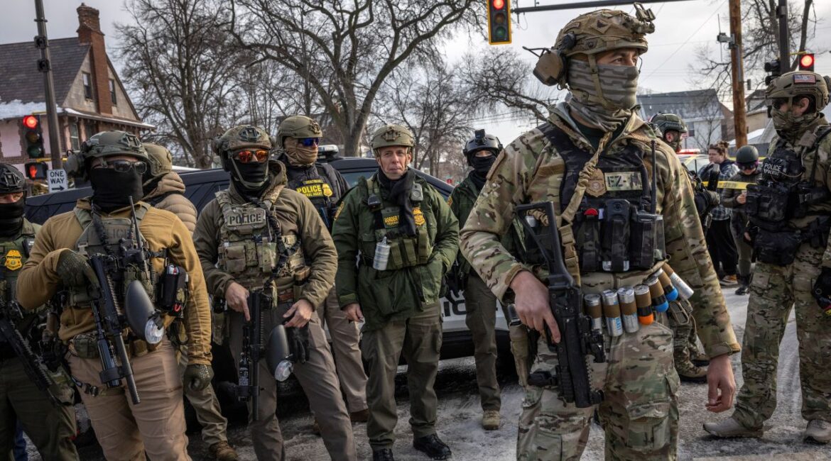 Image of Border Patrol Chief Greg Bovino unmasked and in full paramilitary gear alongside similarly dressed masked federal agents