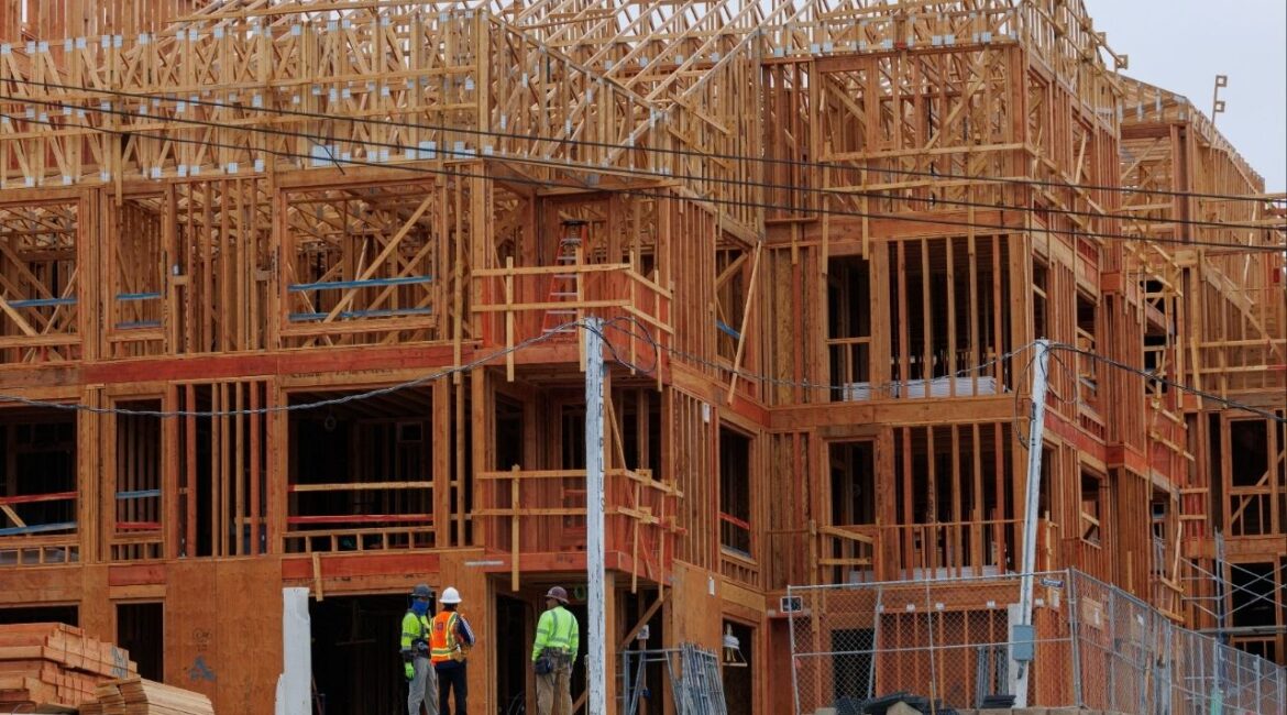 Constriction workers stand in front of a multi-unit residential housing development in Encinitas, California, U.S., October 6, 2025. (Reuters/Mike Blake)