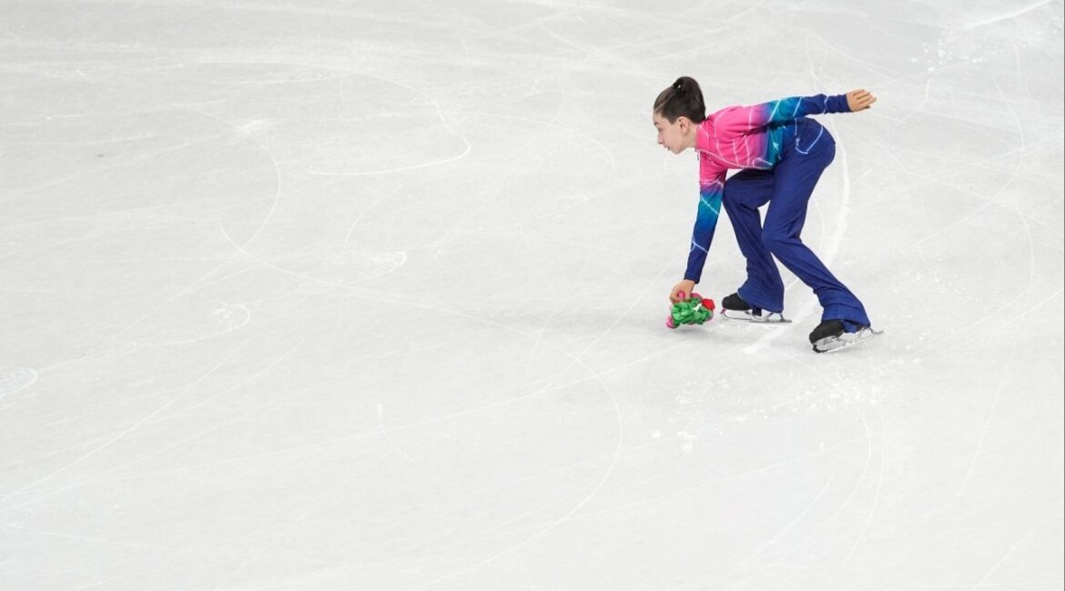 Edoardo, one of the 30 young skaters known as the flower kids, gathers a spectator’s token of appreciation that was thrown after a figure skating performance, at the Winter Olympics skating arena in Milan, February 2026. After spectators throw stuffed toys and bouquets onto the ice in appreciation of a competitor’s routine, the flower kids spring into action. (Weiyi Cai/The New York Times)