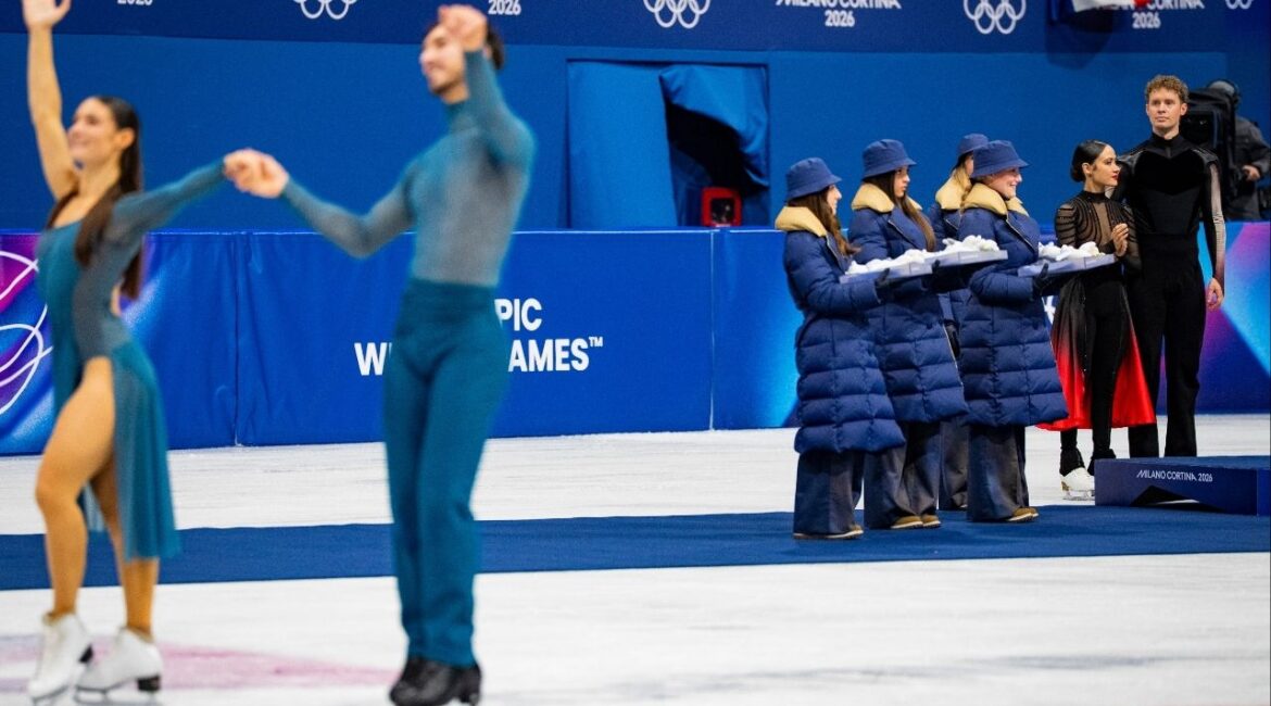 Evan Bates and Madison Chock, right, of the U.S., who won silver, look on as Laurence Fournier Beaudry and Guillaume Cizeron of France greet the crowd after winning gold in the final of the figure skating ice dance free dance during the 2026 Milan Cortina Winter Olympics at the MSK-Competition Rink in Milan, on Wednesday, Feb. 11, 2026. (Vincent Alban/The New York Times)