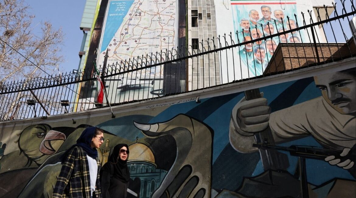 Iranian women walk past an anti-Israeli billboard in Tehran, Iran, February 19, 2026. (Majid Asgaripour/WANA (West Asia News Agency) via Reuters)
