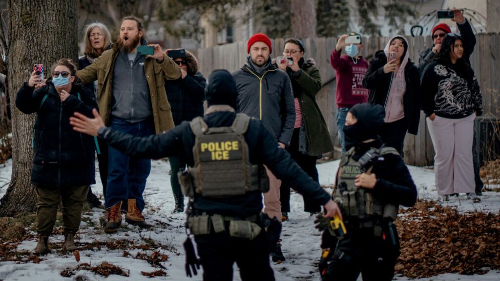 Image of Minneapolis residents videoing and protesting the presence of masked ICE agents