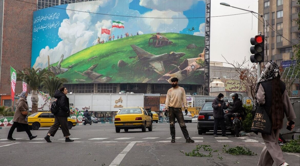 People cross the Valiasr Square, where there’s a new billboard showing American fighter jets being destroyed, in Tehran, Iran, on Feb. 7, 2026. Security officials are monitoring increasingly worrisome signs as President Trump considers another military campaign against Iran. (Arash Khamooshi/The New York Times)