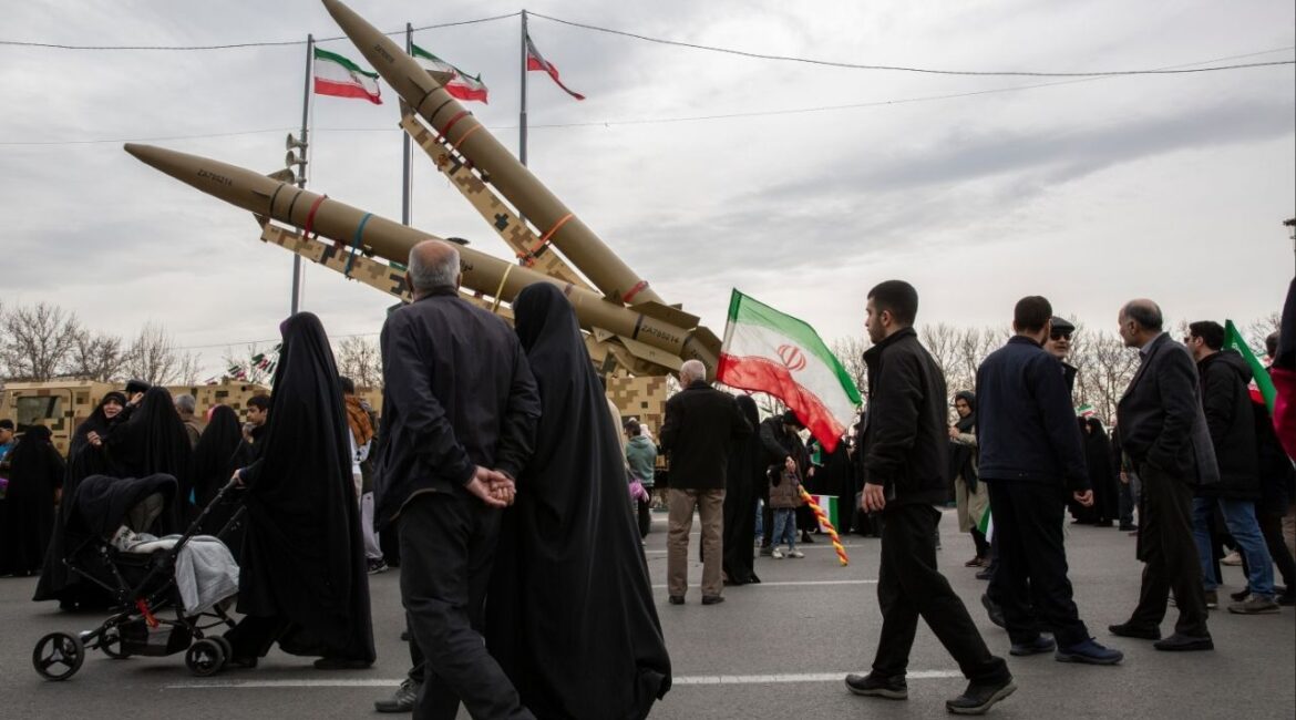 People pass missiles on display during a march marking the anniversary of the Islamic revolution in Tehran, Feb. 11, 2026. The government in Tehran sees capitulating to Washington’s demands on uranium enrichment and ballistic missiles as riskier to its survival than going to war, analysts say. (Arash Khamooshi/The New York Times)