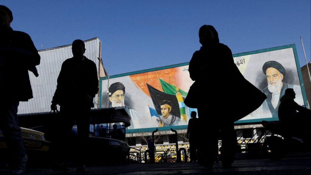 People walk near a mural featuring images of Iran's Supreme Leader Ayatollah Ali Khamenei and leader of Iran's 1979 Islamic Revolution Ayatollah Ruhollah Khomeini, on a street in Tehran, Iran, February 17, 2026. (Majid Asgaripour/WANA (West Asia News Agency) via Reuters)