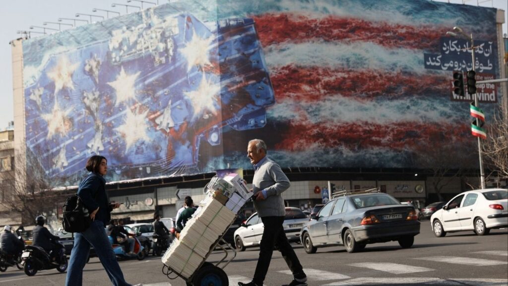 People walk past an anti-U.S. billboard in Tehran, Iran, February 19, 2026. (Majid Asgaripour/WANA (West Asia News Agency) via Reuters)