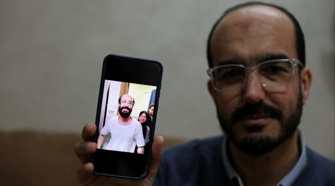 Samer Khaweireh, 45, shows a photo of how he appeared the day he was released from prison four weeks ago after he said he lost 22 kilos of weight in nine months, as he sits in his home in Nablus in the Israeli-occupied West Bank, February 11, 2026.REUTERS/Ammar Awad