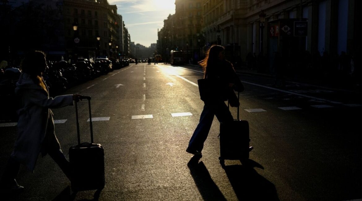Tourists push their luggage as they arrive at Catalonia Square in Barcelona, Spain February 24, 2026. (Reuters/Nacho Doce)
