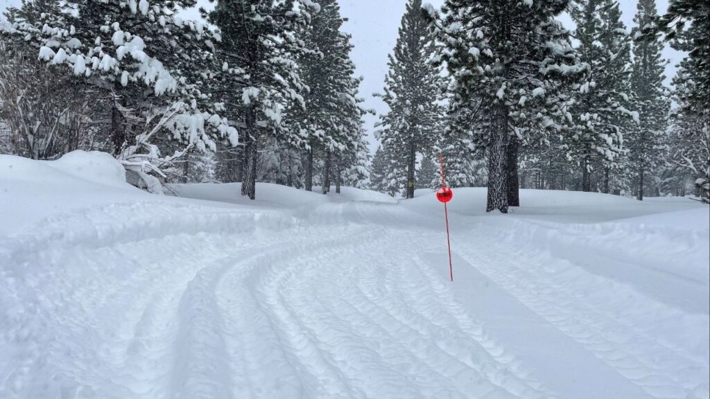 Tread marks from Snow Cat vehicles carrying rescue teams lead into a closed trail at Alder Creek Adventure Center, one of two sites where search crews were launched to try to locate a group of missing skiers after an avalanche in a backcountry slope of California's Sierra Nevada mountains, in Truckee, California, U.S. February 18, 2026. (Reuters/Jenna Greene)