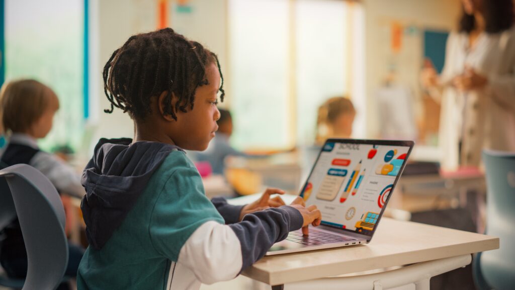 Image of a young Black student working on a laptop in classroom