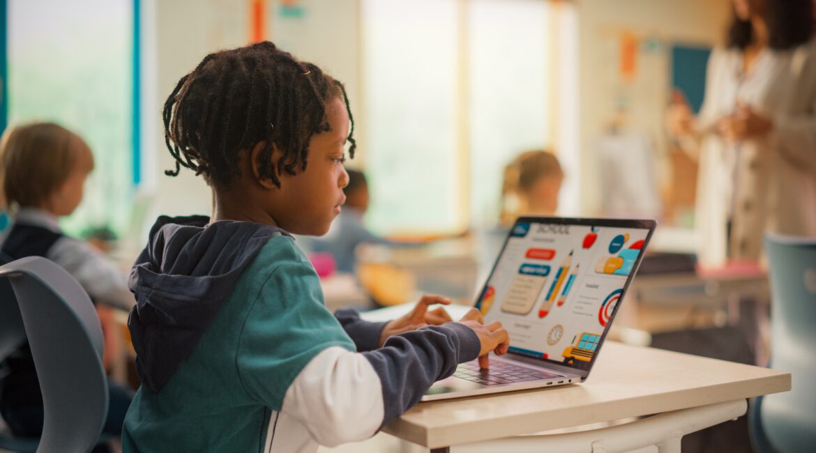 Image of a young Black student working on a laptop in classroom