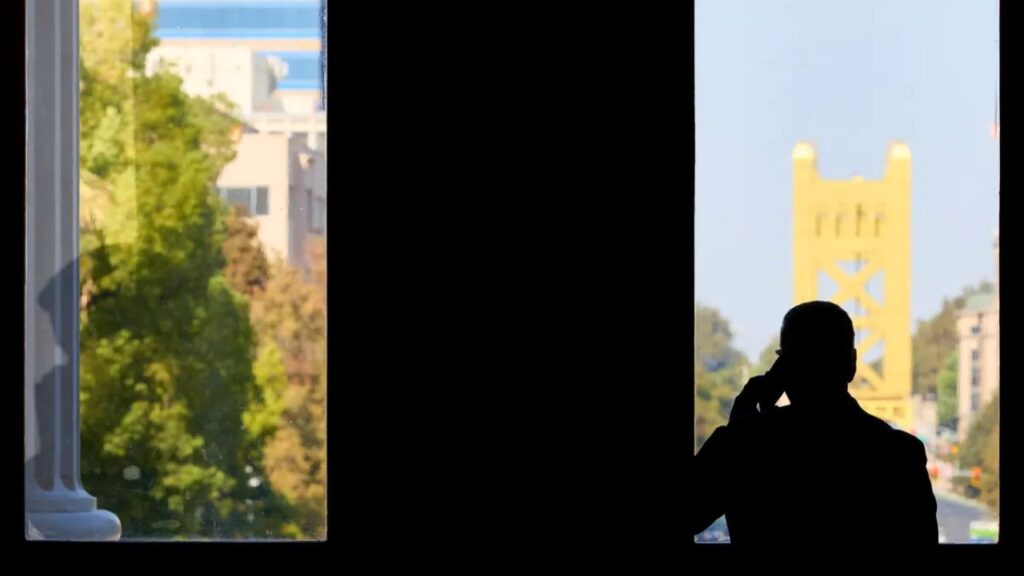 Back silhouette of a man on the phone looking out an office window in Sacramento, California