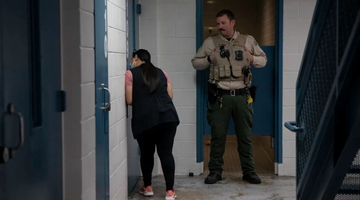 Image of a mental health worker speaking through a jail door to an inmate while a correctional officer watches