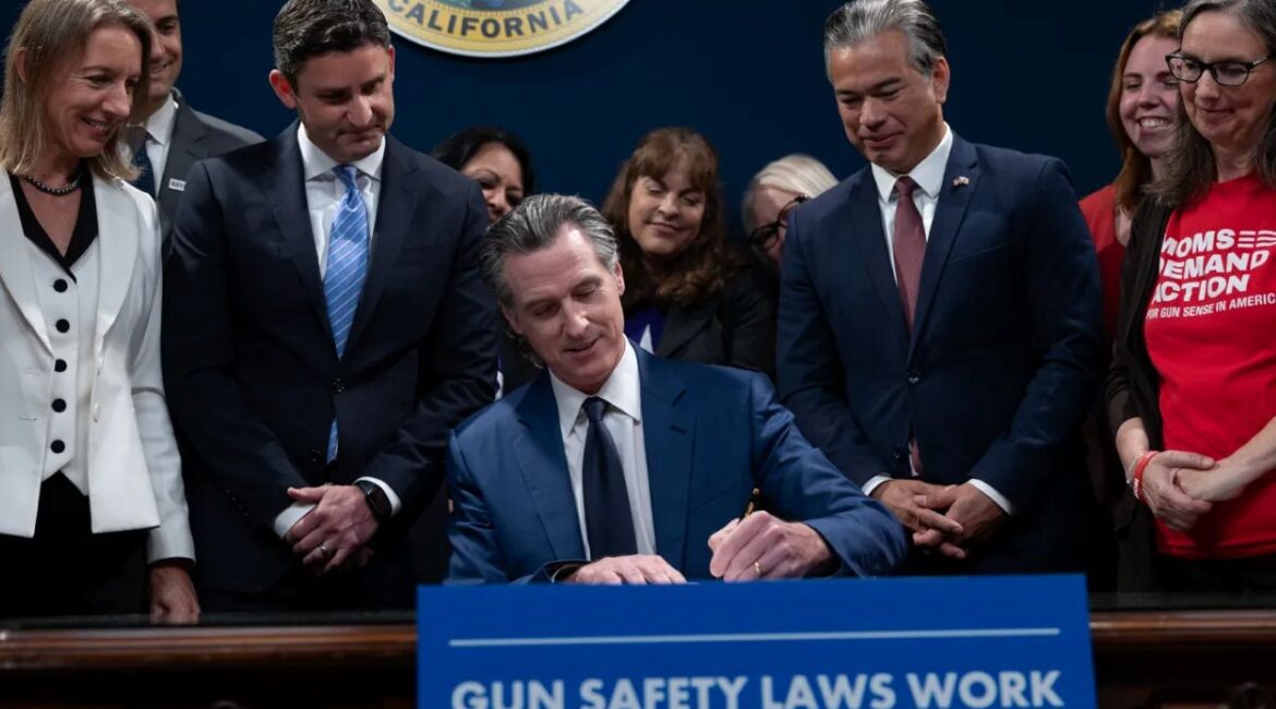 Image of Gavin Newsom signing a gun safety bill at the state Capitol