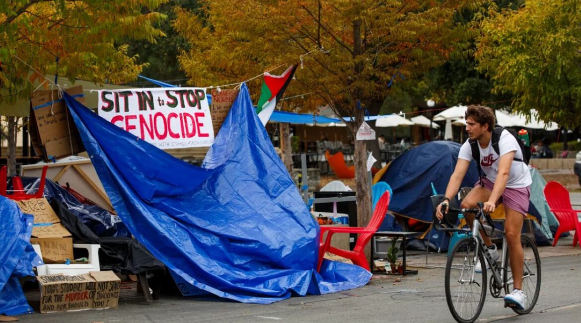 Image of a student biking past a protest at Stanford University