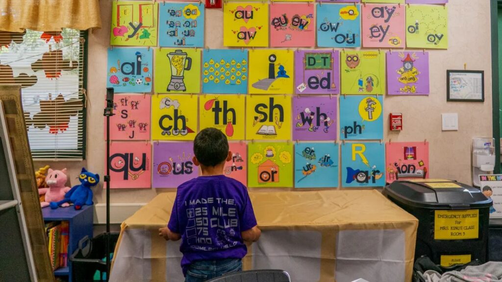Image of a first-grader looking at a colorful phonetic alphabet on the all