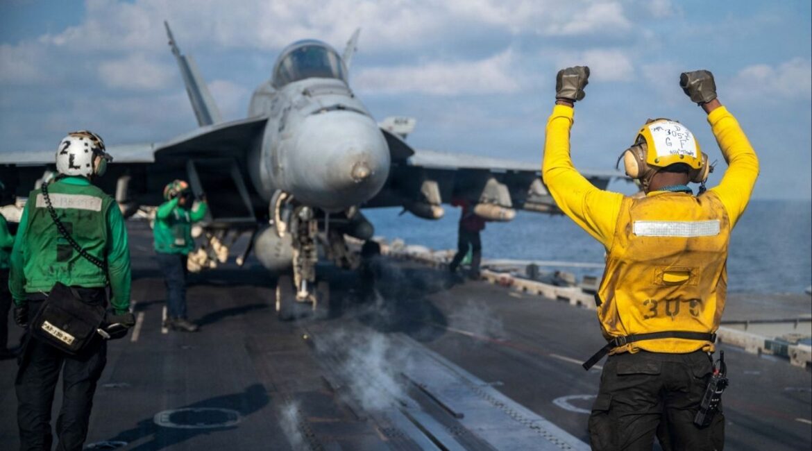 A U.S. Navy sailor signals an F/A-18E Super Hornet on the flight deck of the Nimitz-class aircraft carrier USS Abraham Lincoln in support of the Operation Epic Fury attack on Iran at an undisclosed location March 4, 2026. (Reuters File)