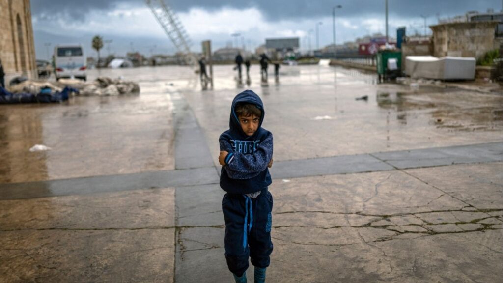 A boy stands outside the stadium in Beirut, Lebanon, that is housing families displaced by the fighting on Friday, March 20, 2026. The number of Lebanese killed rose to more than 1,000, Lebanon’s health ministry said on Thursday. (Diego Ibarra Sánchez/The New York Times)