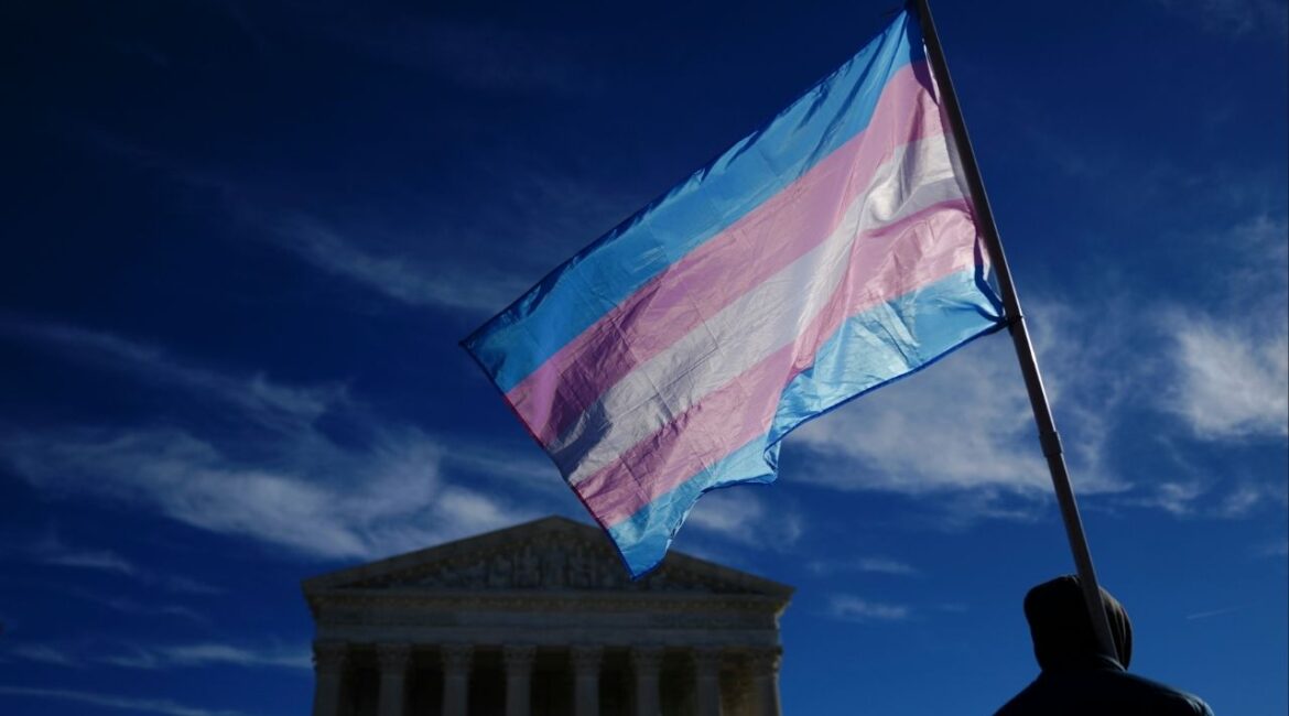 A demonstrator carries a transgender pride flag outside the U.S. Supreme Court as the court hears arguments concerning transgender athletes participating in girls’ sports in Washington, Jan. 13, 2026. The Supreme Court on Monday, March 2, 2026, sided with a group of religious parents, temporarily blocking California from using policies that generally bar public-school teachers from outing transgender students to their parents. (Tierney L. Cross/The New York Times)