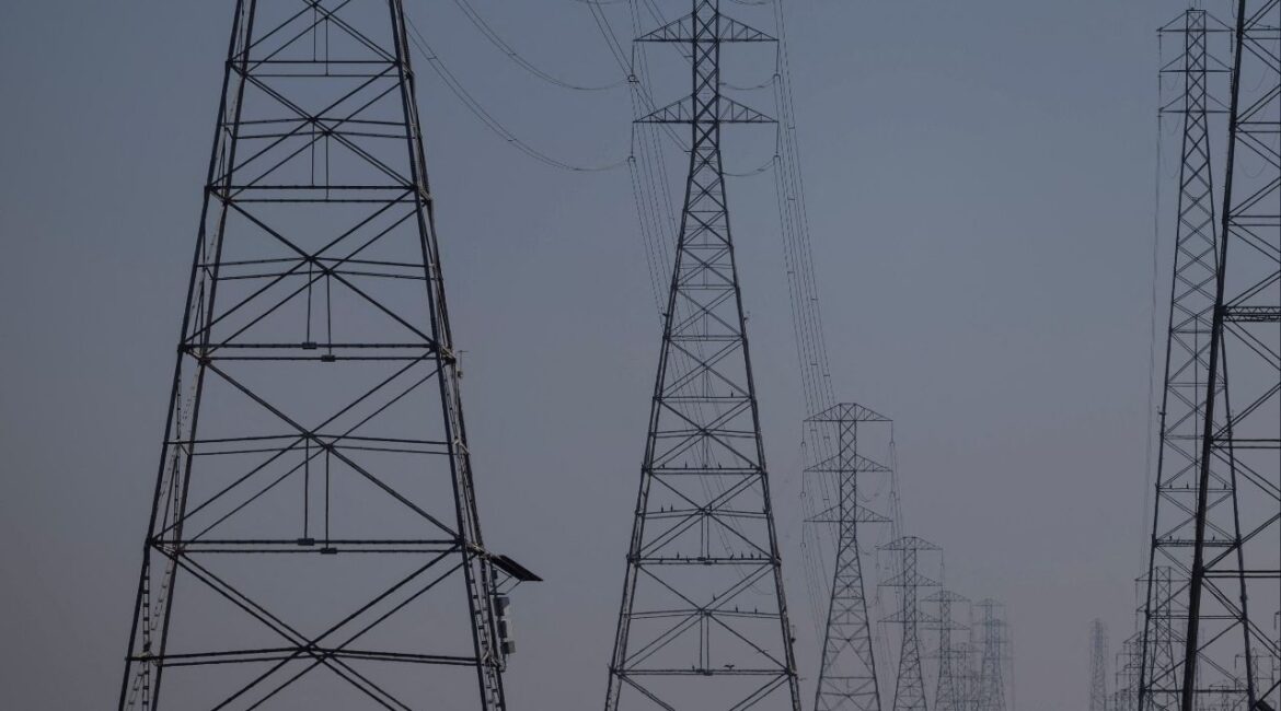 A local resident walks by the power grid towers at Bair Island State Marine Park in Redwood City, California, United States, January 26, 2022. (Reuters/Carlos Barria)