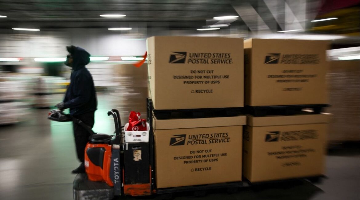 A postal worker transports boxes filled with packages at the United States Postal Service (USPS) Processing & Distribution Center in Los Angeles, California, U.S., December 2, 2025. (Reuters/Daniel Cole)