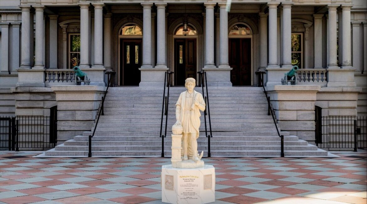 A statue of Christopher Columbus stands in front of the Eisenhower Executive Office Building at the White House Complex in Washington after being installed early Sunday morning, March 22, 2026. A statue of Christopher Columbus was installed on the grounds of the White House early Sunday morning, as part of President Trump’s effort to position the explorer as a hero after monuments to him were removed across the country. (Jason Andrew/The New York Times)