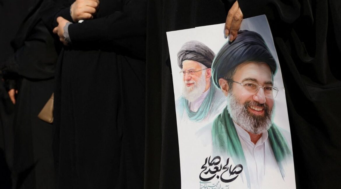A woman holds an image of Iran's new supreme leader, Mojtaba Khamenei, alongside late Iranian Supreme Leader Ayatollah Ali Khamenei, during a funeral ceremony for the Iranian military commanders who were killed in strikes, amid the U.S.-Israeli conflict with Iran, in Tehran, Iran, March 11, 2026. (Reuters File)