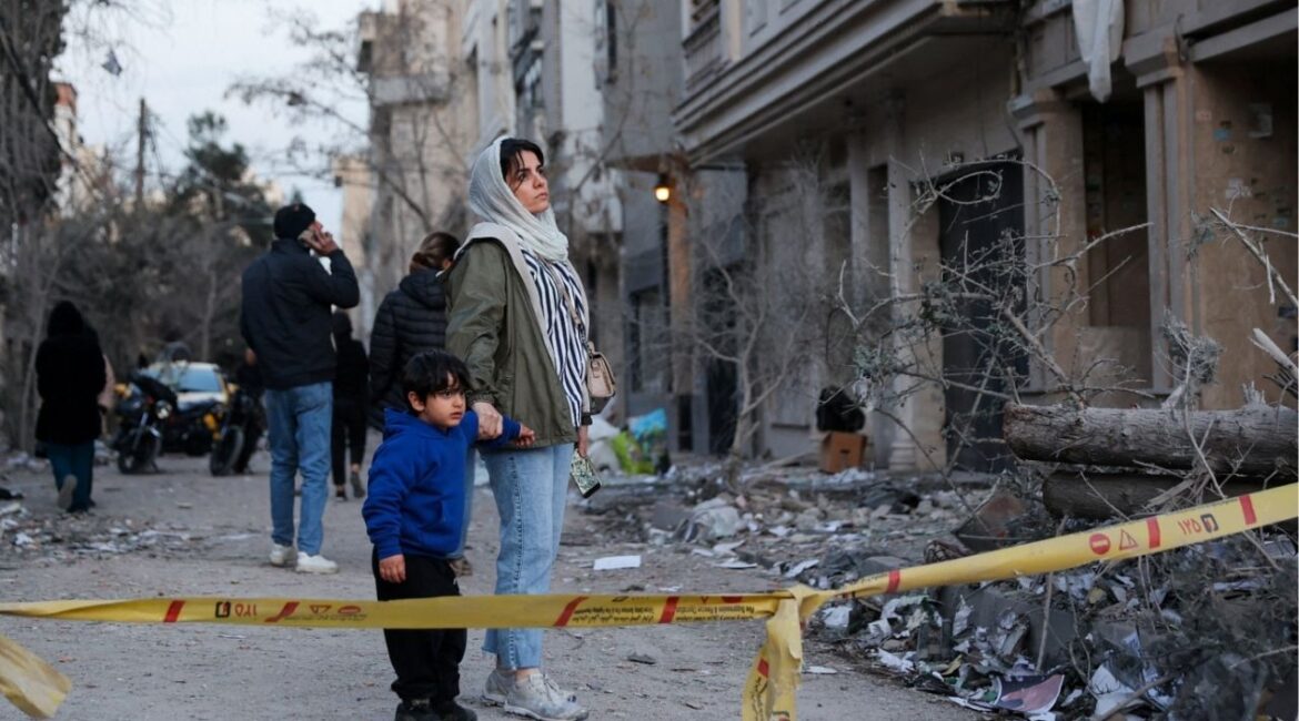 A woman with her child looks at the aftermath of an Israeli and the U.S. strike on a police station, amid the U.S.-Israel conflict with Iran, in Tehran, Iran, March 2, 2026. (Majid Asgaripour/WANA (West Asia News Agency) via Reuters)