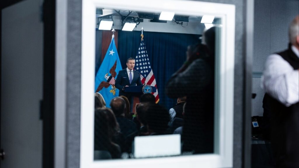 Defense Secretary Pete Hegseth is reflected in a window as he speaks to reporters during a press briefing at the Pentagon in Arlington, Va., on Tuesday, March 31, 2026. Hegseth conceded on Tuesday that Iran retains the ability to retaliate despite a monthlong U.S.-Israeli bombing campaign but repeated claims that Iran’s military capabilities had been severely degraded, in his first public briefing on the war in nearly two weeks. (Eric Lee/The New York Times)