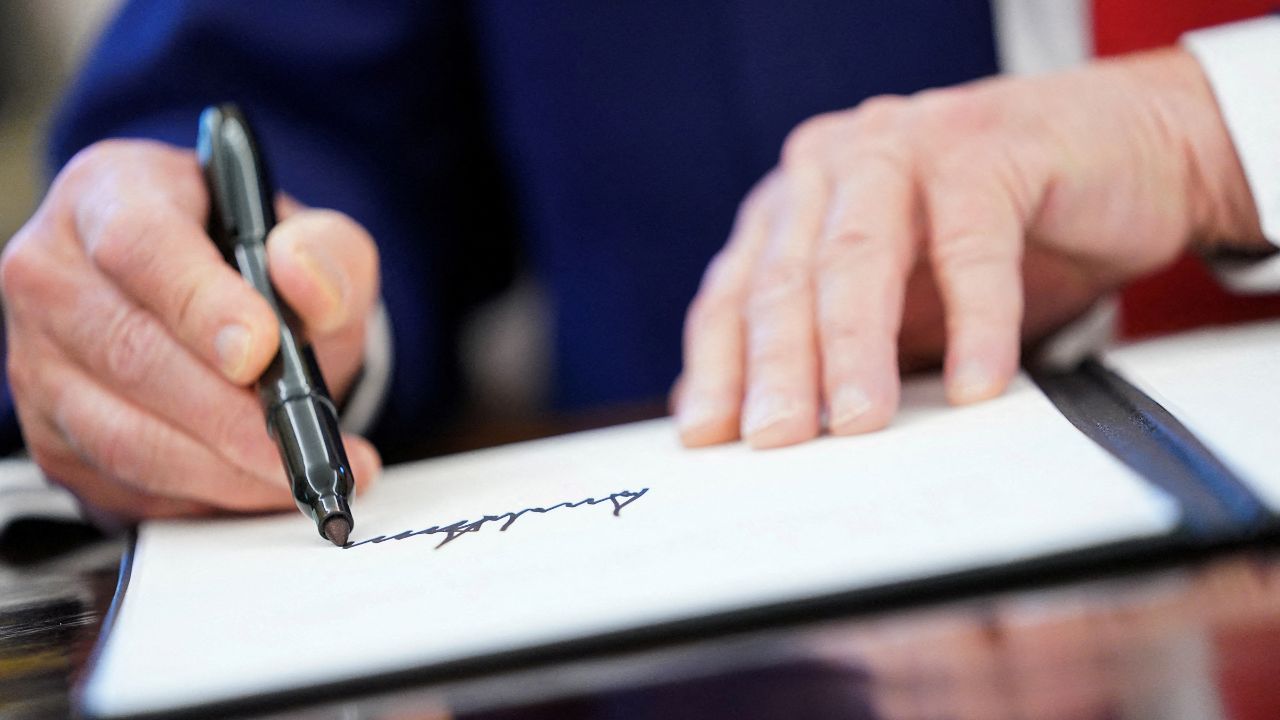 FILE PHOTO: U.S. President Donald Trump writes his signature, as he signs executive orders and proclamations in the Oval Office at the White House in Washington, D.C., U.S., April 9, 2025. REUTERS/Nathan Howard/File Photo