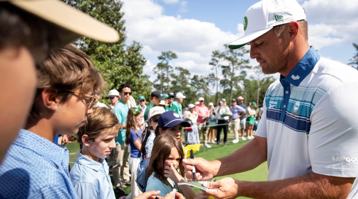 Image of Bryson DeChambeau signing autographs for youngsters at the 2025 Masters