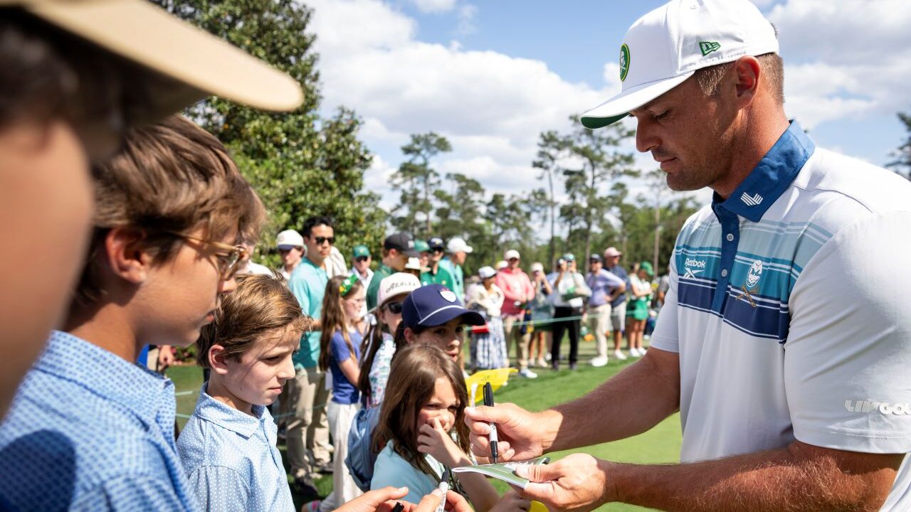 Image of Bryson DeChambeau signing autographs for youngsters at the 2025 Masters