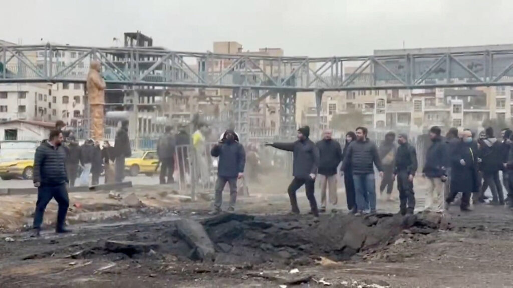 People stand at an affected area on the street, following a reported strike, amid the U.S.-Israeli conflict with Iran, in Tehran, Iran, in this screengrab from a a handout video released March 10, 2026. (Iranian Red Crescent Society/Handout via Reuters)
