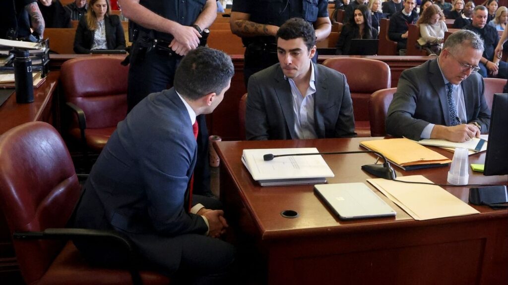 Luigi Mangione, seated second from left, confers with one of his attorneys as he awaits the start of a pretrial hearing in State Supreme Court in Manhattan on Thursday morning, Dec. 11, 2025. Lawyers for Luigi Mangione asked a federal judge on Wednesday, March 18, 2026, to push his murder trial back until early next year, arguing that they cannot prepare for a separate state trial at the same time. (Jefferson Siegel/The New York Times)